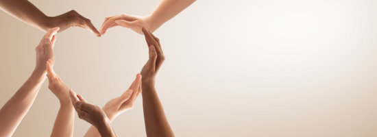 Several hands of different skin tones form a heart shape against a light background.